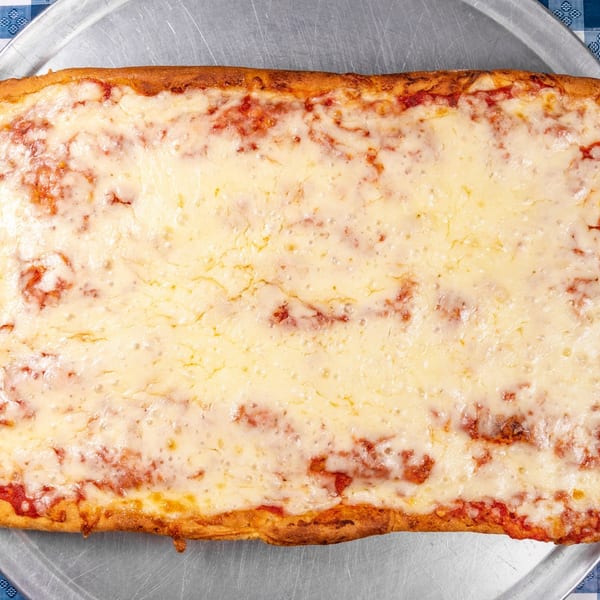 A rectangular cheese pizza with a golden crust sits on a metal tray, on a blue and white checkered tablecloth.