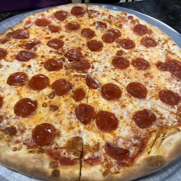 A whole pepperoni pizza with melted cheese and a golden crust on a metal tray.
